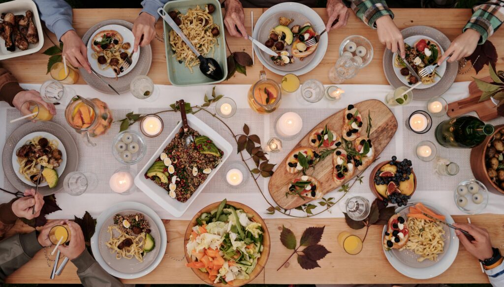 Overhead shot of a vibrant dining table setup with pasta, salads, and decorative candles, capturing a festive gathering.