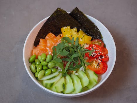 pexels-photo-12814860-12814860 Close-up of a vibrant poke bowl with fresh veggies, salmon, and seaweed on a neutral background.